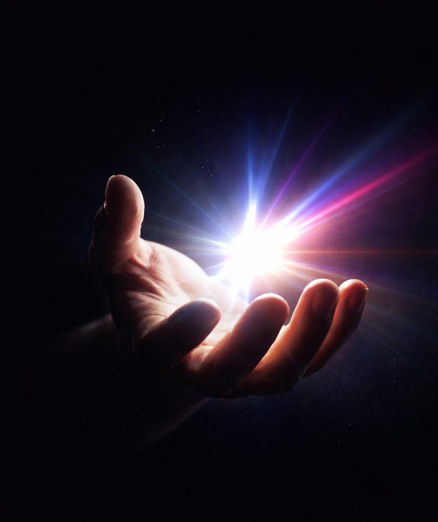 Mão aberta segurando um ponto de luz azul, violeta e magenta